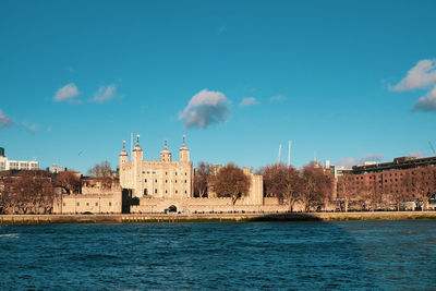 Buildings by river against sky in city
