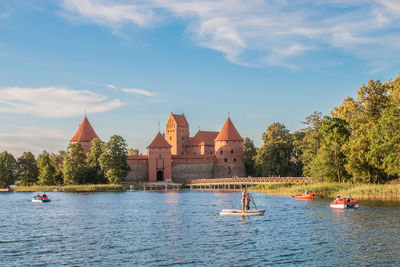 Scenic view of river by buildings against sky