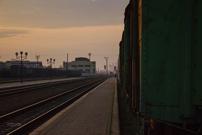 Railroad tracks in city against sky at sunset