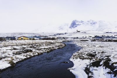 Scenic view of river amidst snow covered field against sky