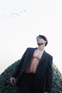 Portrait of young man standing against clear sky