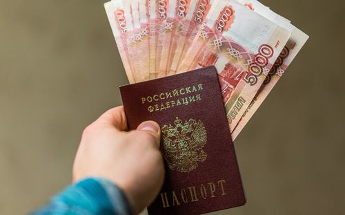 Close-up of man holding money and passport against brown background