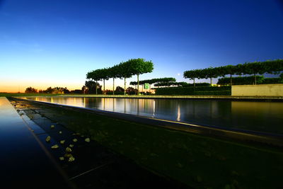 Swimming pool by lake against sky at sunset