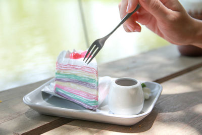 Close-up of hand holding coffee cup on table