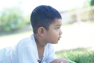 Portrait of cute boy looking away on field