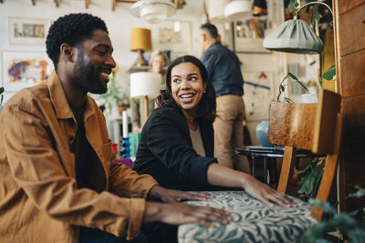 Smiling female shop owner assisting male customer while buying chair at store