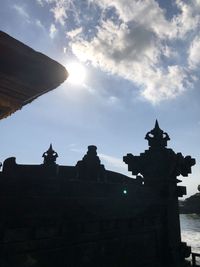 Low angle view of silhouette statue against building against sky