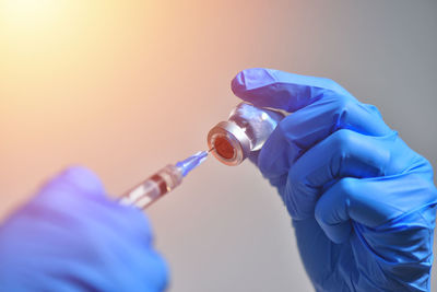 Close-up of hand holding bottle against blue background