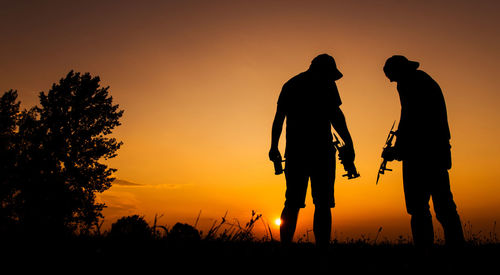 Silhouette man walking on field against sky during sunset