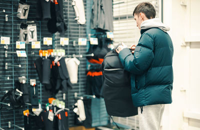 A young guy chooses a backpack in a store.