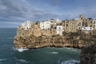 Buildings by sea against sky