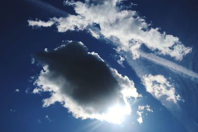 Low angle view of sunlight streaming through clouds