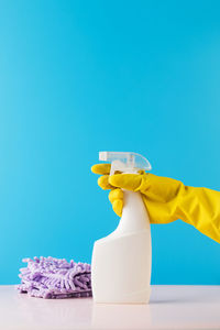 Cropped hand of dentist holding dentures against blue background