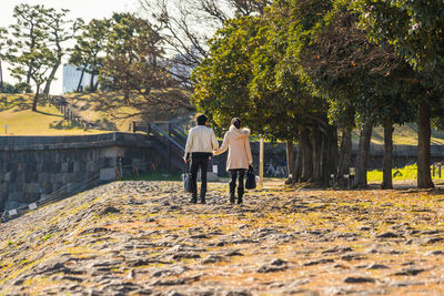 Rear view of couple walking by trees