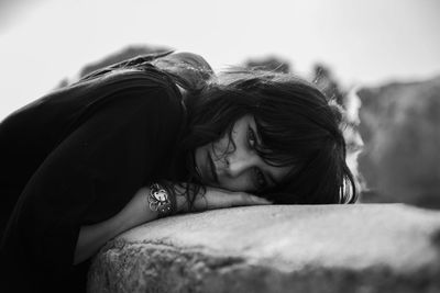 Close-up of girl looking down on bed against sky