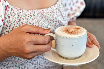 Midsection of woman holding coffee cup