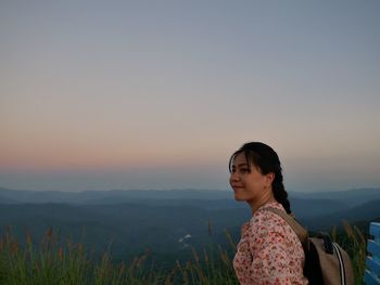 Woman smiling against sky during sunset