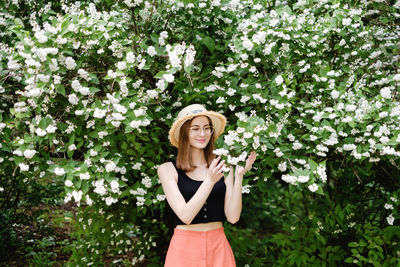 Portrait of a smiling young woman standing against plants