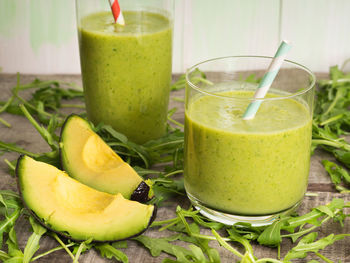 Smoothie in glasses and arugula on table