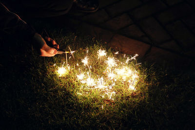 High angle view of hand holding sparkler at night