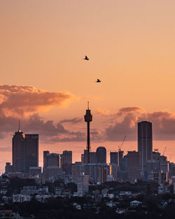 Buildings in city against sky at sunset