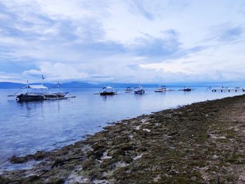 Sailboats moored on sea against sky