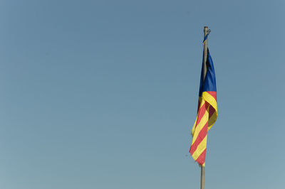 Low angle view of flag against clear blue sky