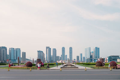 People on street amidst buildings in city against sky