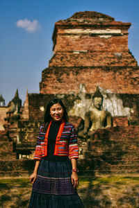 Portrait of woman standing against historic building