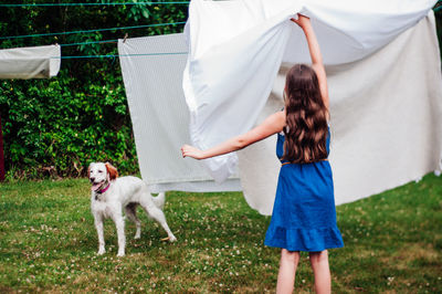 Rear view of girl drying clothes in back yard