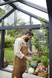 Rear view of man preparing food in greenhouse