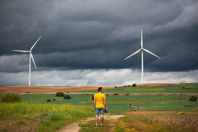 Rear view of windmill on field against sky