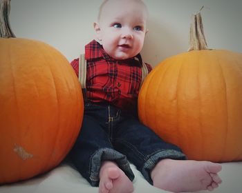 Smiling cute baby boy sitting amidst pumpkins