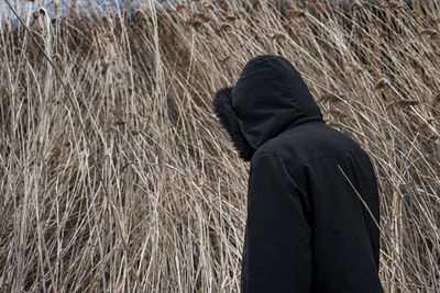 Side view of man standing against dried plants