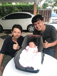 Portrait of happy father and daughter sitting outdoors