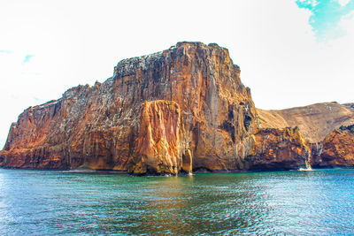Rock formations by sea against sky
