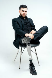 Young man sitting on chair against white background