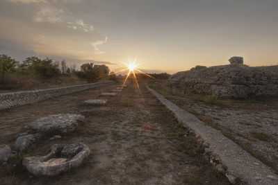 Road amidst rocks against sky during sunset