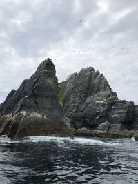 Rock formation in sea against sky