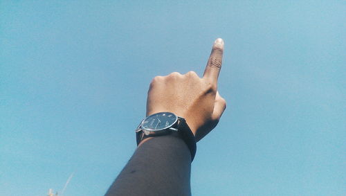 Cropped hand of person pointing towards clear sky