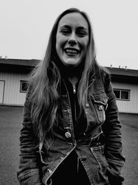 Portrait of smiling young woman standing against built structure