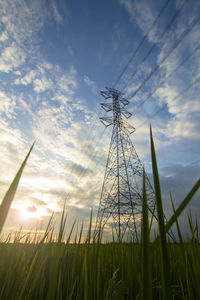 Low angle view of electricity pylon on field against sky