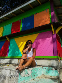 Full length of woman sitting against colorful built structure