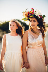 Friends standing at beach against sky