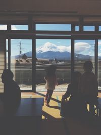 People in building by window against mt fuji