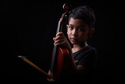 Portrait of boy holding camera over black background