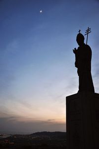 Low angle view of statue against sky at sunset