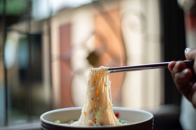 Cropped hand holding noodles with chopstick