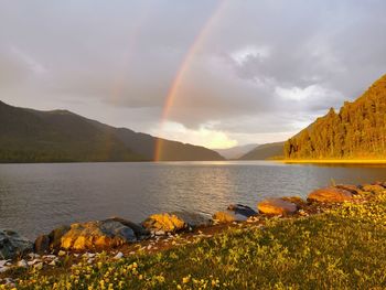 Scenic view of rainbow over lake against sky