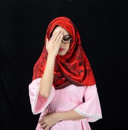 Midsection of woman with pink hair against black background